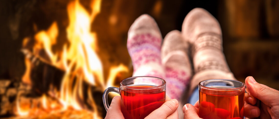 Couple relaxing with mulled wine at romantic fireplace on winter evening